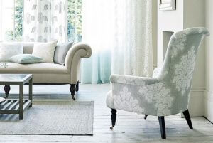 An image showing sheer curtains in a room with a sofa and armchair