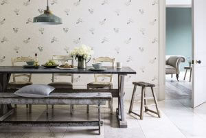 An image showing a vintage looking wallpaper on a wall with a wooden table and chairs in a room