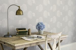 An image showing an old table against a wall with flower decorations and old books